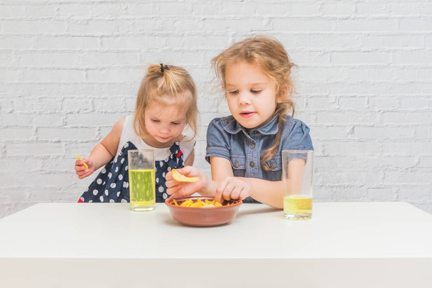 girl, baby eating potato chips and drinking soda, not healthy food - Foto, Bild