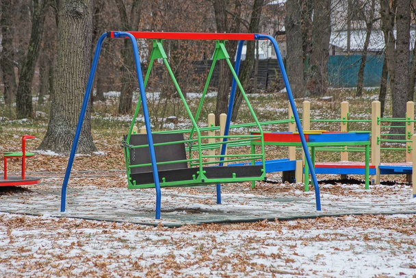 yksi iso värillinen rauta keinu leikkikentällä talvipuistossa valkoinen lumi
 - Valokuva, kuva