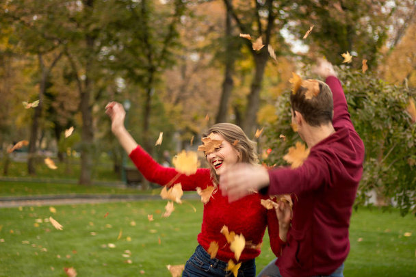 ένα ζευγάρι ρίχνει επάνω κίτρινα φύλλα, σφένδαμνος, μέχρι, χαζεύεις, το φθινόπωρο. ημερομηνία. το γέλιο και τη διασκέδαση - Φωτογραφία, εικόνα