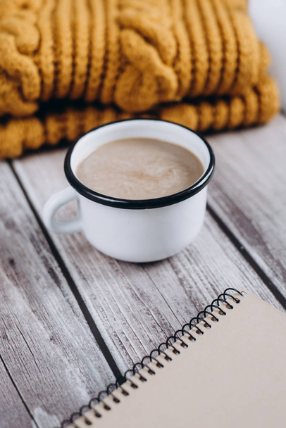 Winter cozy concept. Flat lay of brown scarf, notebook, candle and coffee with milk drink on wooden table - Foto, immagini