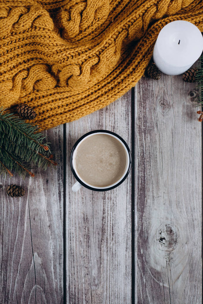 Taza de café con leche, vela, bultos, ramas de abeto y bufanda naranja caliente en la mesa de madera.Concepto de invierno. Piso tendido, vista superior
.  - Foto, Imagen