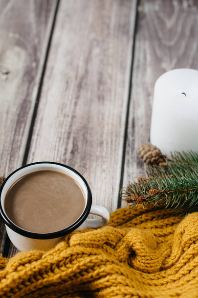 Cup of coffee  with milk, candle, bumps, spruce branches and warm orange scarf on wooden table.Winter concept. Flat lay, top view.  - Foto, Imagem