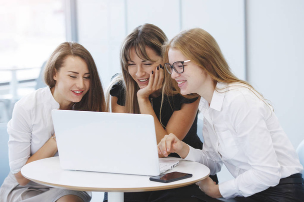 Team of office staff. Three business women are sitting at a table with a laptop and are planning a corporate development concept for the future. Teamwork. Gender equality. - Foto, Imagen