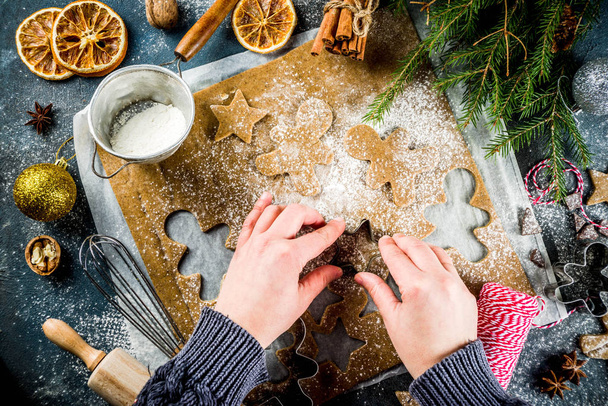 Fille cuisine Noël maison biscuits étoiles en pain d'épice, hommes en pain d'épice, plat laïc, vue sur le dessus, avec des ingrédients accessoires pour la cuisson. Fond en béton bleu foncé, espace de copie, mains dans l'image
 - Photo, image
