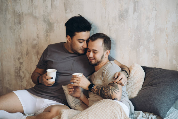 Perfect morning begins with lover and coffee in bed. Two guys resting in bed. - Foto, Imagen