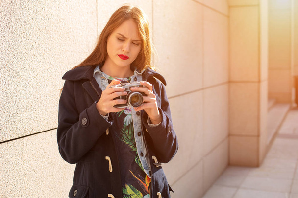 Ευτυχισμένος hipster κορίτσι κάνει φωτογραφία με ρετρό κάμερα στην πόλη δρόμο. Ήλιος φωτοβολίδα - Φωτογραφία, εικόνα