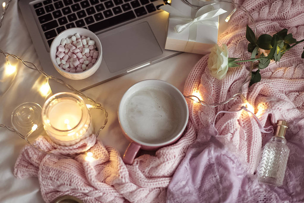 Cozy decor. A cup of cappuccino. Candle in a glass jar, pink knitted blanket, rose, laptop. Cozy. Autumn. - Foto, afbeelding