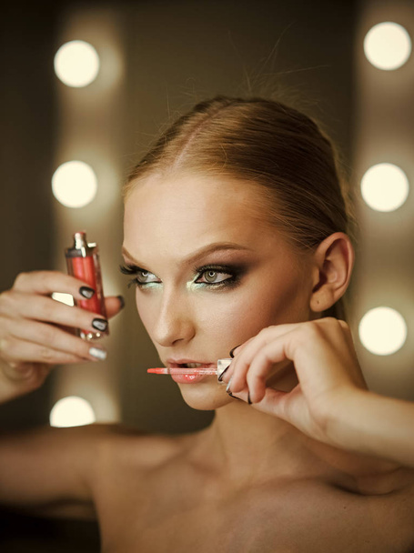 Beautiful young woman applying lips makeup with cosmetic brush. - Photo, Image