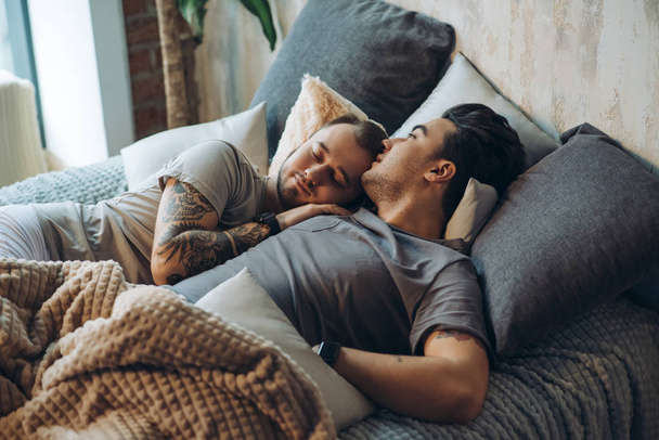 A homosexual couple on bed in studio with loft interior - Φωτογραφία, εικόνα