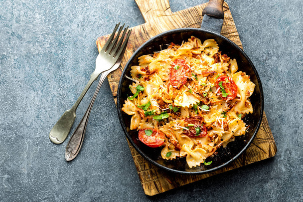 pasta farfalle with roasted meat and tomatoes in a frying pan - Foto, imagen