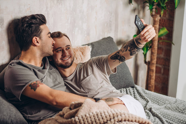 Happy gay couple taking selfie on bed at home - Foto, Imagen