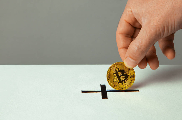 El hombre pone la donación de bitcoin en la ranura en forma de cruz cristiana. Copiar espacio para texto
 - Foto, imagen