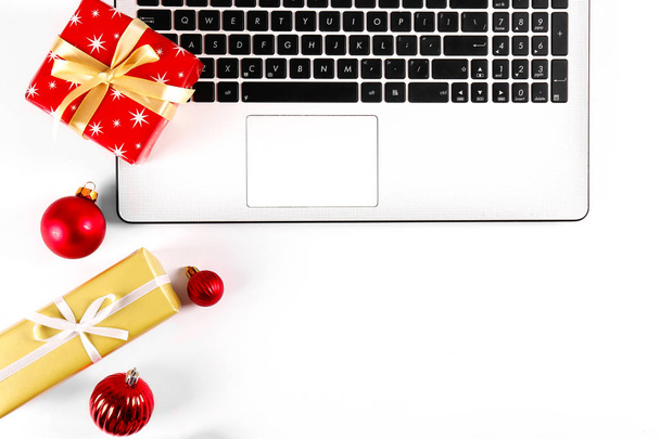 Online shopping for winter holidays concept. Flat lay composition with white laptop, black keyboard and traditional festive Christmas decoration. Close up, copy space, background, top view. - Foto, afbeelding