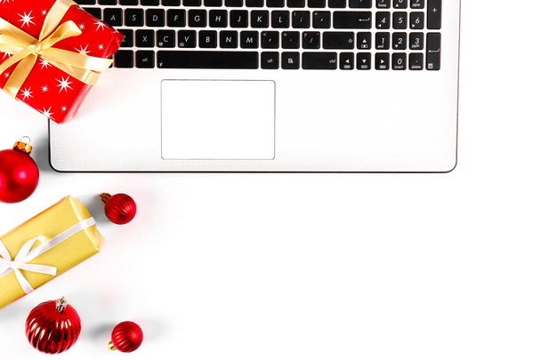 Online shopping for winter holidays concept. Flat lay composition with white laptop, black keyboard and traditional festive Christmas decoration. Close up, copy space, background, top view. - Photo, image
