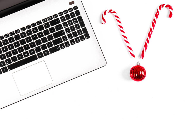 Online shopping for winter holidays concept. Flat lay composition with white laptop, black keyboard and traditional festive Christmas decoration. Close up, copy space, background, top view. - Foto, Bild