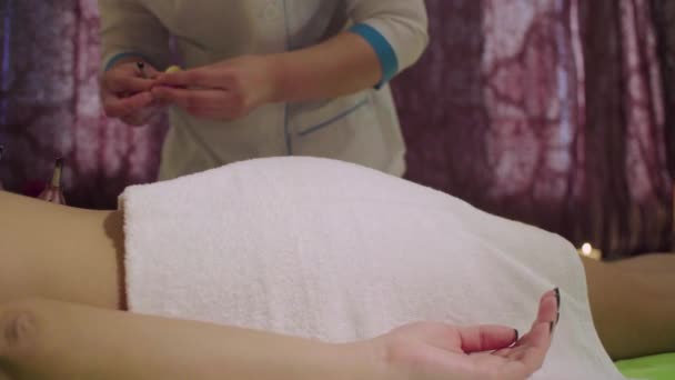 Chinese doctor heating reflexology points to a young woman - Materiał filmowy, wideo