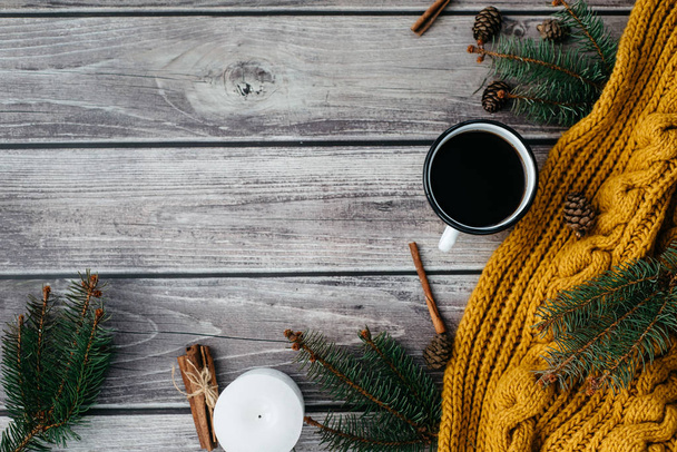 Cup of coffee  , candle, bumps, cinnamon, spruce branches and warm orange scarf on wooden table. Winter concept. Flat lay, top view.  - Fotografie, Obrázek