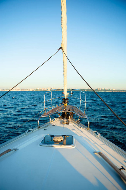 Ніс яхти, що пливе в морі під час сходу сонця. Вид з носа білої яхти на морі, на узбережжі на фоні
. - Фото, зображення