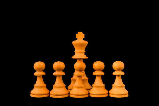 White King protected by wall of pawns with sense of protection and defense, standard chess wooden piece on black background - Photo, Image