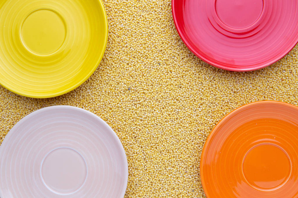 Yellow millet background, yellow, biege, orange, red plate on it - Φωτογραφία, εικόνα
