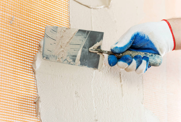Рабочий накладывает штукатурку на пюре на стену лопатой
. - Фото, изображение