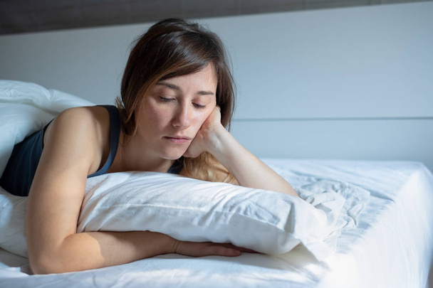 Сумна жінка не може спати лежачи в її ліжку вдома
 - Фото, зображення