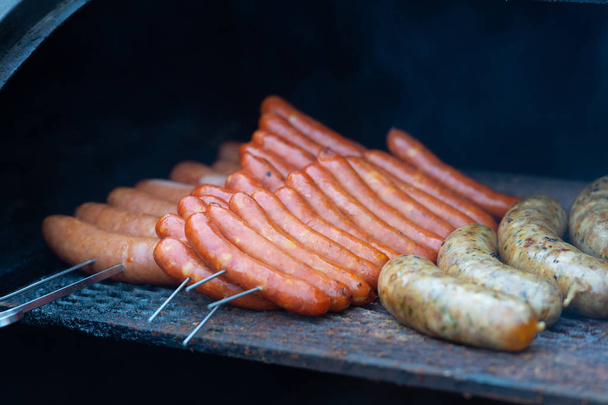 verse worst en hotdogs grillen buitenshuis op een gasbarbecue grill. - Foto, afbeelding