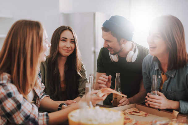 Cheerful young people having fun while enjoying pizza and drinks - Foto, afbeelding