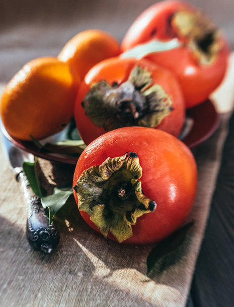Heldere sappige persimmon op de achtergrond van een houten tafel. Winter vruchten - Foto, afbeelding