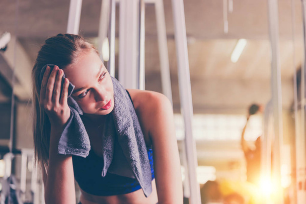 Tired woman from workout wiping sweat with towel in sports gym  - Fotoğraf, Görsel