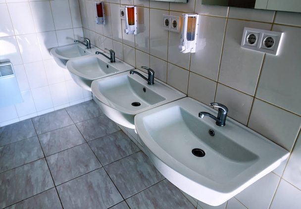 four clean washbasins with faucet in the toilet - Photo, Image