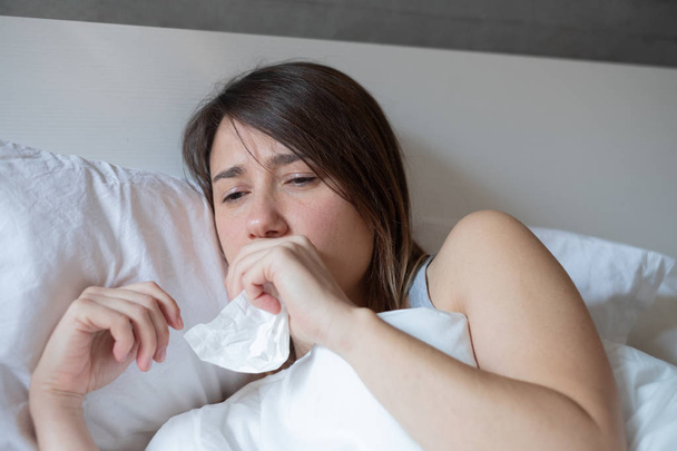 Young woman coughing covered by warm duvet - Foto, immagini