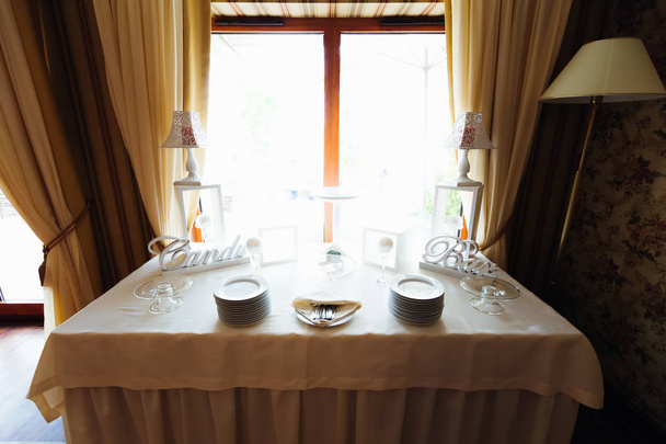 窓の近くのレストランで白いテーブル クロスをかけたテーブル。キャンディ バーの装飾と板のテーブル - 写真・画像
