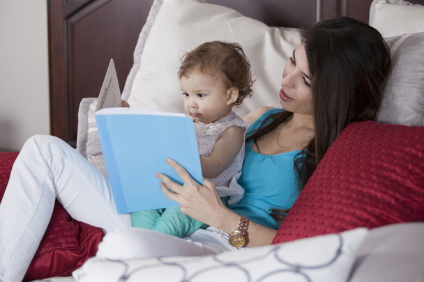 mother and daughter in bed reading book - Photo, Image