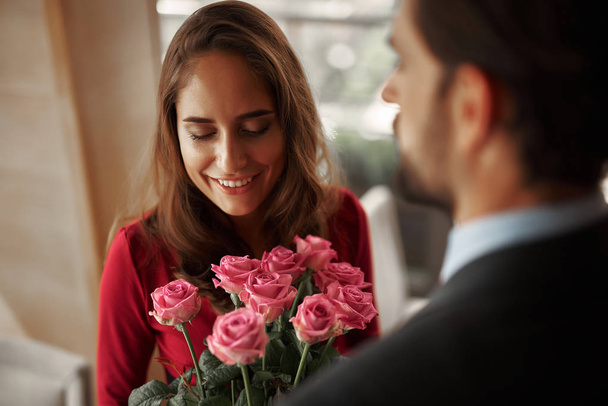 Young man in suit presenting lady bunch of roses - Photo, image