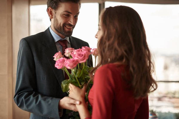 Uomo sorridente che presenta mazzo donna di fiori
 - Foto, immagini