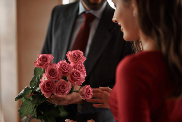 Jonge man voorstellende lachende vrouw roze rozen - Foto, afbeelding