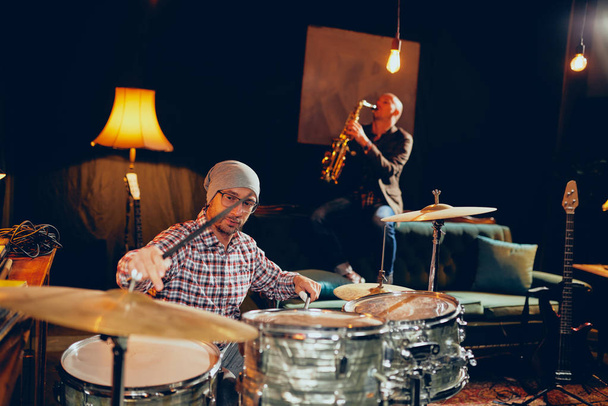 Deux hommes jouant de la batterie et du saxophone en home studio
. - Photo, image