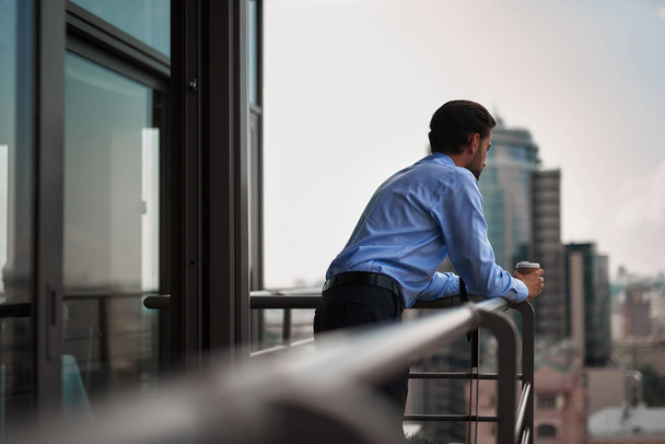 One male worker drinking coffee on office balcony - Valokuva, kuva