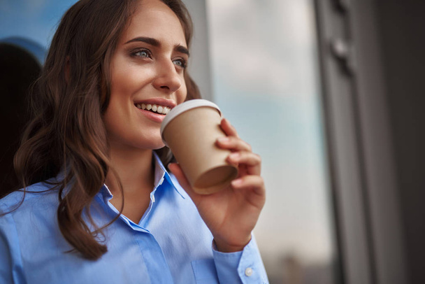 Female worker drinking coffee on office balcony - Фото, зображення