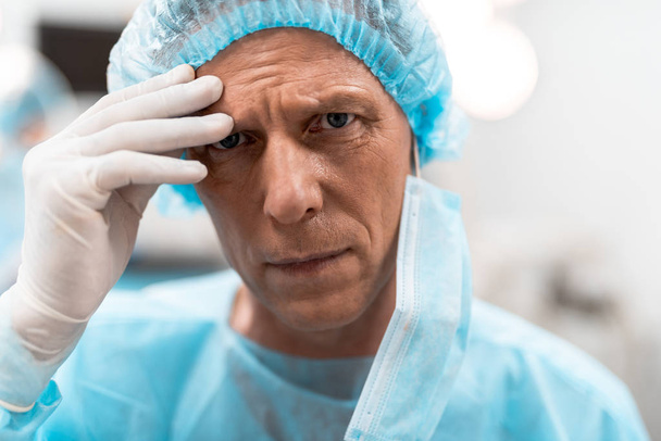 Unhappy doctor looking and touching his forehead - Photo, image
