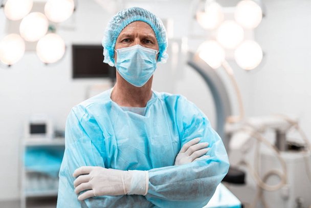 Serious doctor standing with his arms crossed and looking - Foto, afbeelding