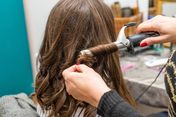Cabeleireiro curling mulher cabelo com ferro elétrico curler tong. Cabeleireiro fazendo penteado menina. Salão de beleza
. - Foto, Imagem