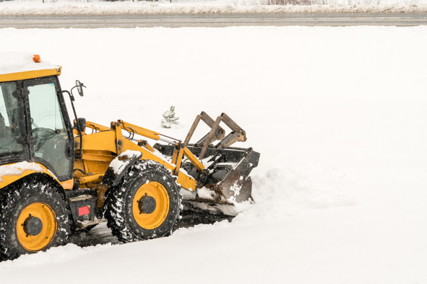 Snow removal. Wheel loader machine or vehicle removing snow from the roads in winter. - Photo, Image