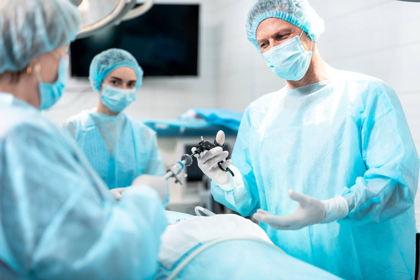 Nurse giving laparoscopic instrument to doctor during surgery - Foto, Imagem