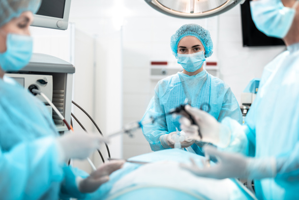 Enfermera sosteniendo máscara de oxígeno en la cara del paciente durante la operación quirúrgica
 - Foto, imagen