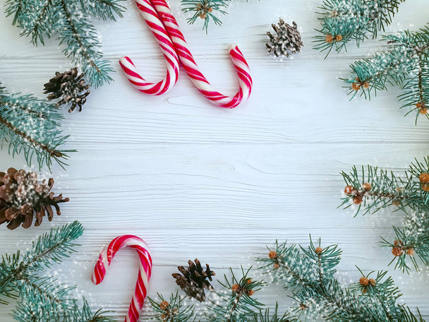 Christmas tree branch, pinecone, candy on a white wooden background - Fotoğraf, Görsel
