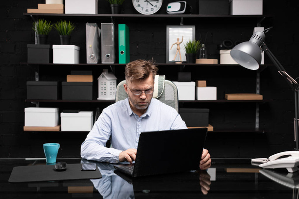 Vakava liikemies työskentelee kannettavan tietokoneen parissa ja juo kahvia
 - Valokuva, kuva