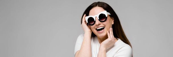 Porträt eines emotional schönen Plus-Size-Models mit Sonnenbrille, das im Studio steht und in die Kamera blickt - Foto, Bild