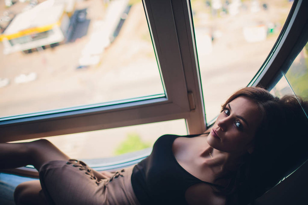 Beautiful girl in dress lies on window sill in round window - Foto, Bild